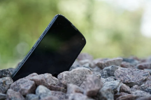 Broken cellphone abandoned and lost among the gravel