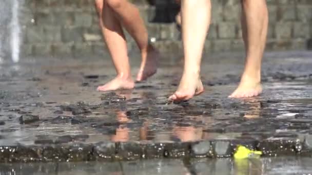 Barefoot legs play with fountain water jets. People in town play with water in the fountains, happy and carefree, concept of freedom and happiness in childhood, starting summer and tourist cities. — Stock Video