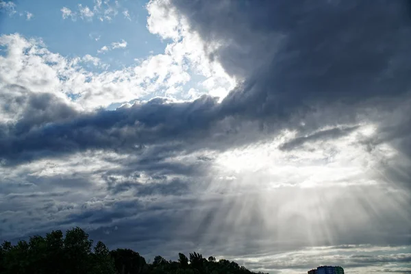 Stralen van heldere zon gluren uit achter donkere wolken, zon pauze na Storm — Stockfoto