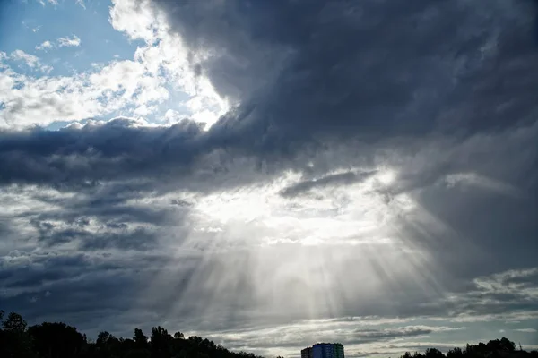 Rays of bright sun peep out from behind dark clouds, sun break after storm