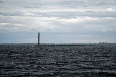 Fırtına ve şiddetli rüzgardan sonra nehir üzerinde beacon ve iskele sakin. Ortasında deniz feneri var. Geliştirilmiş gökyüzü.