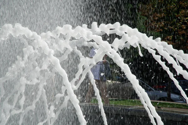 Fontaine au soleil contre-jour. Les fontaines jaillissant de l'eau pétillante du tuyau dans le parc — Photo