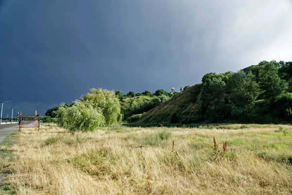 Černá obloha nad zeleným kopcem, před bouří — Stock fotografie