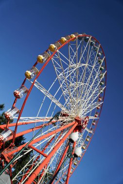 Atlıkarınca. Mavi arka planda dönme dolap. Büyük tekerleğin arabaları..