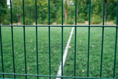 Yapay çim ve yeşil ağlı gerilmiş ağ ile parkta oyun parkı.