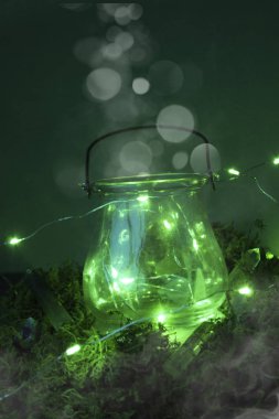 Yosun ve ateş böceği ve sis ve duman ve bokeh ile yeşil arka planda sihirli kazan