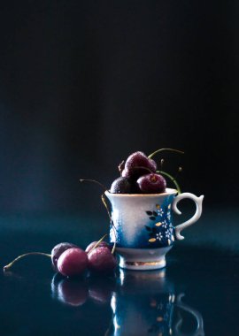 Taze kiraz porselen fincan ile Karanlık natürmort