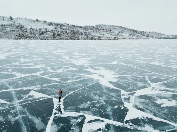 Ragazza che cammina sul ghiaccio del lago Baikal. L'intera superficie del ghiaccio è incrinata. Il ghiaccio si è appena alzato . — Foto Stock