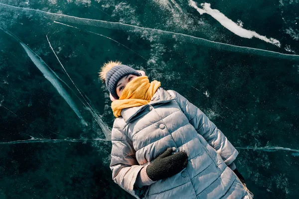 Ragazza si trova sulla superficie ghiaccio trasparente e guarda nel cielo e si gode di vacanze e bel tempo. guarda le nuvole e pensa a quanto sia bella la natura della Siberia — Foto Stock