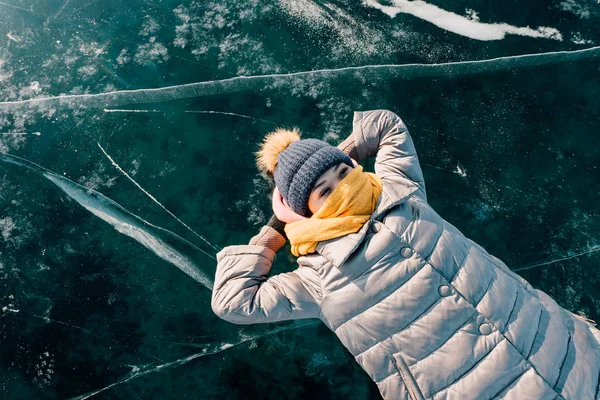 Ragazza si trova sulla superficie ghiaccio trasparente e guarda nel cielo e si gode di vacanze e bel tempo. guarda le nuvole e pensa a quanto sia bella la natura della Siberia — Foto Stock