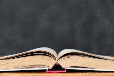 Okul tahta arka plan karşı ahşap okul masası üzerinde açık kitap