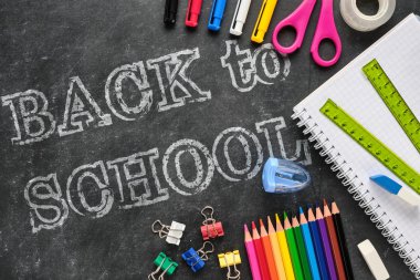 Cetvel, defter, kalem, kalem, makas gibi tebeşir tahtası üzerinde okul malzemeleri ile okul yazıgeri