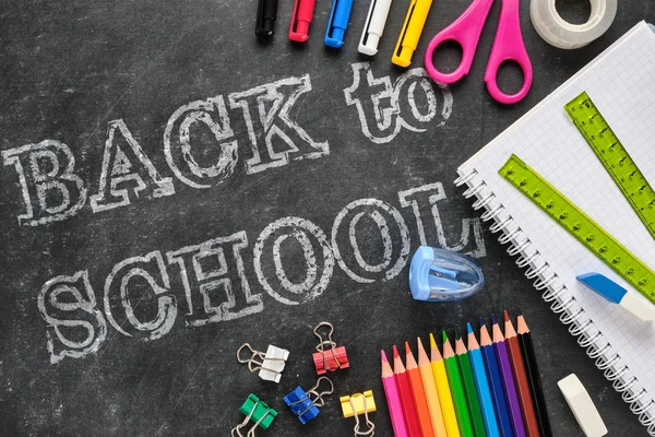 Cetvel, defter, kalem, kalem, makas gibi tebeşir tahtası üzerinde okul malzemeleri ile okul yazıgeri