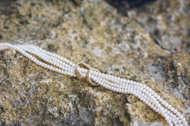 Kayalarda yüzükler ve inci kolye. Plaj düğünü konsepti