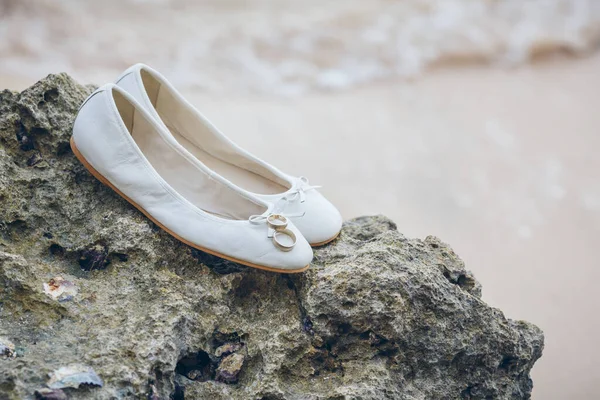 Beautiful bridal shoes on the rocks near ocean. Beach wedding concept