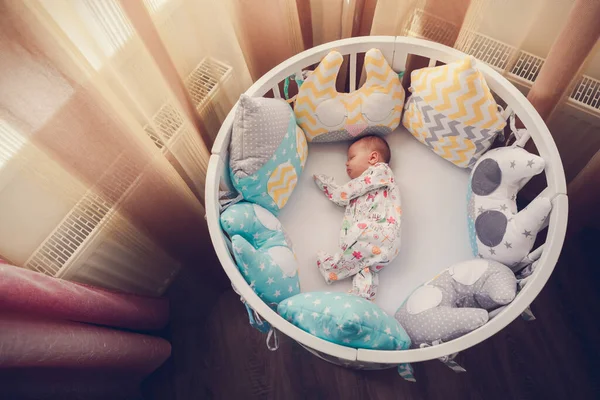 Cute newborn little girl sleeping in a white round crib