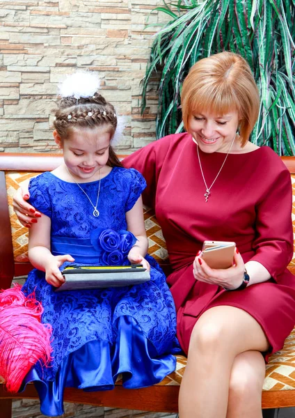 Mom and daughter spend time with their gadgets. Shooting in Studio.