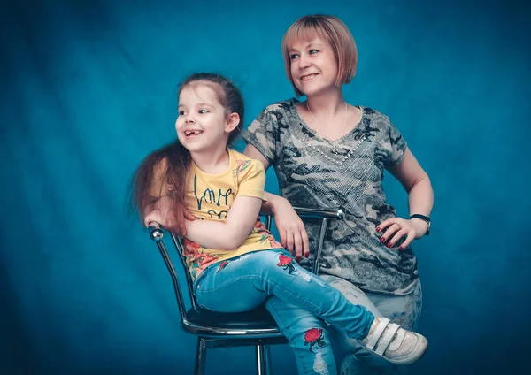 Studio shooting. Happy mother and daughter look away from the camera.