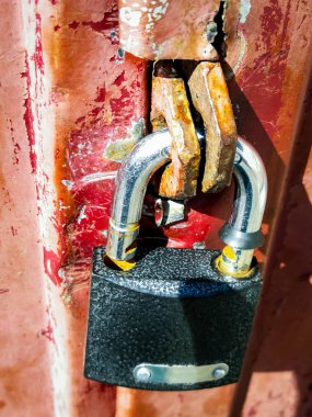 Açık bir asma kilit bir demir kapıya asılı.