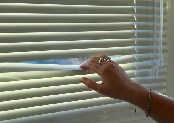 Woman Hand Bends Rail Horizontal Blinds Look Out Window — Stock Photo, Image