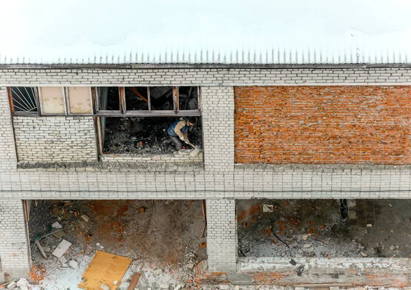 In een industrieel gebouw werknemer breekt een bakstenen muur met een moker — Stockfoto