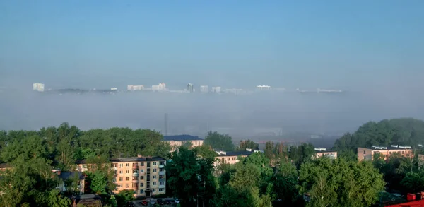 Vista de la ciudad en la niebla, que parece flotar en las nubes . — Foto de Stock