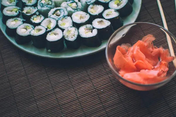 Sushi casero con jengibre y palos de sushi en alfombra de madera . — Foto de Stock