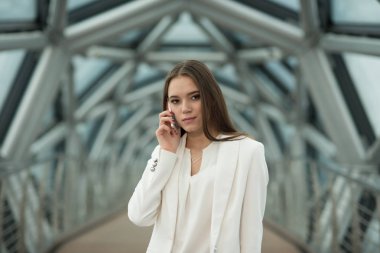 koridorda duran ve telefonu tutan genç bir esmer kız