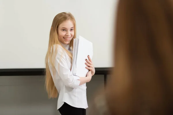 Jong meisje zakenvrouw in casual kleding, zitten aan een tafel nauw kijken naar documenten, werken op computer — Stockfoto