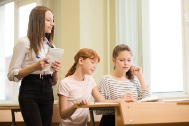 3 öğrenci kız masa başında oturan