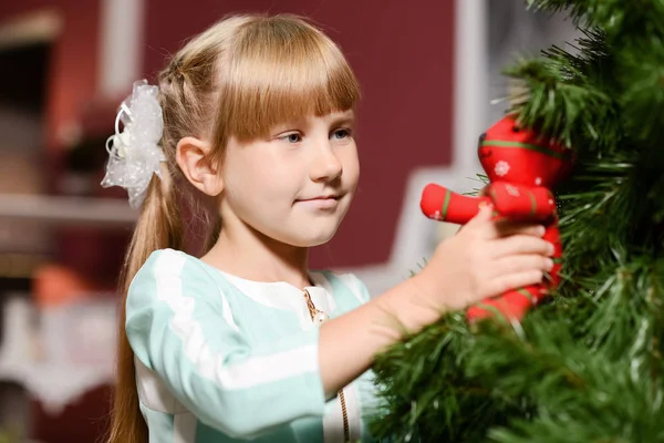 La chica en el lado de la chimenea blanca, decorar un árbol de Navidad con juguetes —  Fotos de Stock