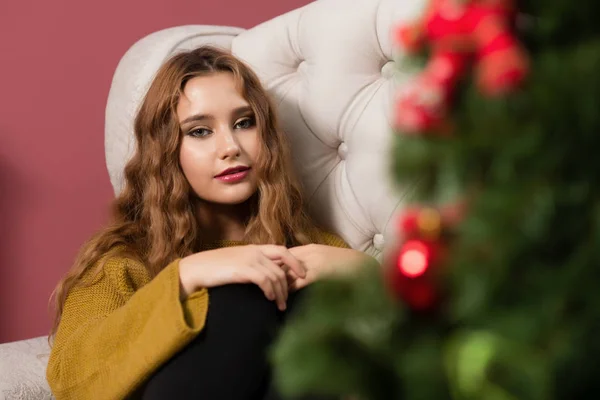 The girl in the next to the white fireplace, decorate a Christmas tree with toys — Stock Photo, Image