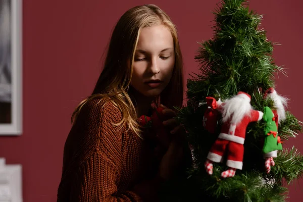 Το κορίτσι στην επόμενη στο λευκό τζάκι, διακοσμήσει ένα χριστουγεννιάτικο δέντρο με τα παιχνίδια — Φωτογραφία Αρχείου