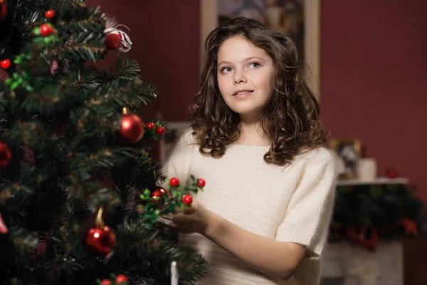 A menina no ao lado da lareira branca, decorar uma árvore de Natal com brinquedos — Fotografia de Stock