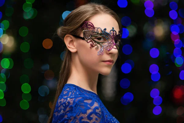 Menina em um vestido e máscara, em um fundo de uma árvore de Natal — Fotografia de Stock