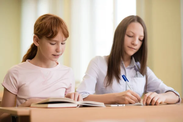 2 student girls are sitting at a Desk Stock Picture