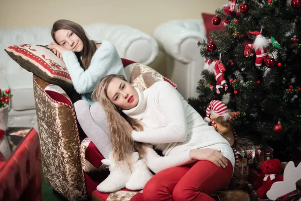 La 2 chica en el lado de la chimenea blanca, decorar un árbol de Navidad con juguetes —  Fotos de Stock