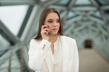 koridorda duran ve telefonu tutan genç bir esmer kız