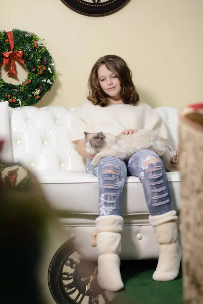 The girl in the next to the white fireplace, decorate a Christmas tree with toys — Stock Photo, Image