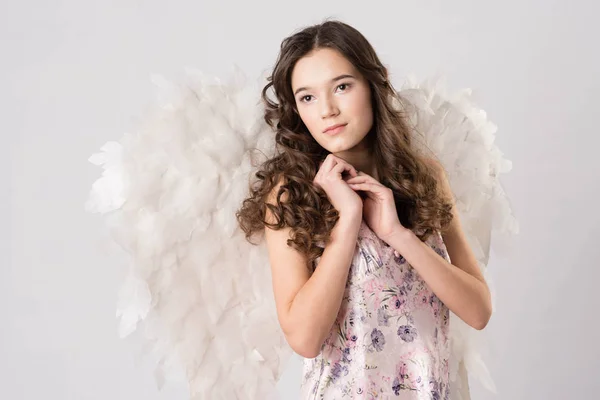 Brunette girl in white with angel wings stands — Stock Photo, Image