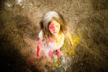 gür saçları parlak bir kız gülümsüyor, saç, yüz ve eller Holi renklerde 