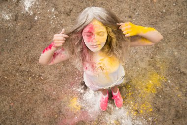 gür saçları parlak bir kız gülümsüyor, saç, yüz ve eller Holi renklerde 