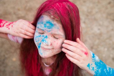 parlak esmer kız gülümseyerek ve onun saç yüzünü ve ellerini renkli Holi 