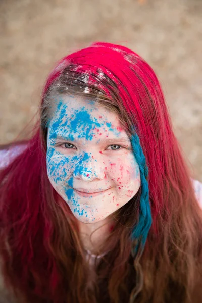 Menina morena brilhante sorrindo e seu rosto de cabelo e mãos em cores Holi — Fotografia de Stock