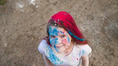 parlak esmer kız gülümseyerek ve onun saç yüzünü ve ellerini renkli Holi 