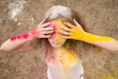 gür saçları parlak bir kız gülümsüyor, saç, yüz ve eller Holi renklerde 