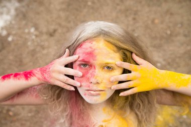 gür saçları parlak bir kız gülümsüyor, saç, yüz ve eller Holi renklerde 