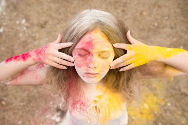 gür saçları parlak bir kız gülümsüyor, saç, yüz ve eller Holi renklerde 