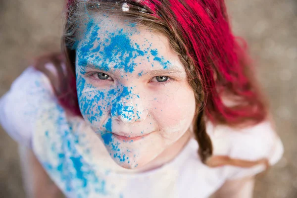 Menina morena brilhante sorrindo e seu rosto de cabelo e mãos em cores Holi — Fotografia de Stock