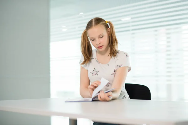 A menina em uma camiseta branca e com caudas sentadas à mesa e brincando — Fotografia de Stock